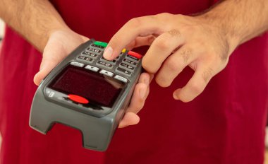 Ödeme makinesi ve daktilo makinesi tutan adam, yakın çekim. Kredi kartı okuyucu, POS terminal ödeme kavramı.