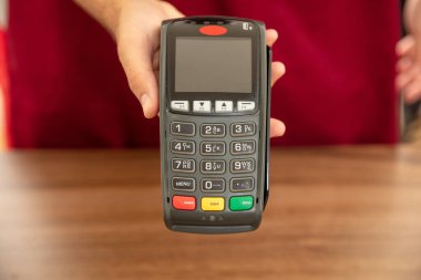 Kasiyer, ödeme için POS terminalini kredi kartıyla sunuyor. Bankacılık, alışveriş ve NFC teknoloji konsepti ile irtibatsız ödeme.