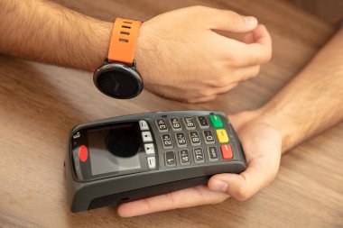 Mobil ödeme, akıllı saat NFC, saha iletişimi kablosuz teknolojisi. POS makinesi ve akıllı saat ile kasiyer ve müşteri elleri, yakın görünüm
