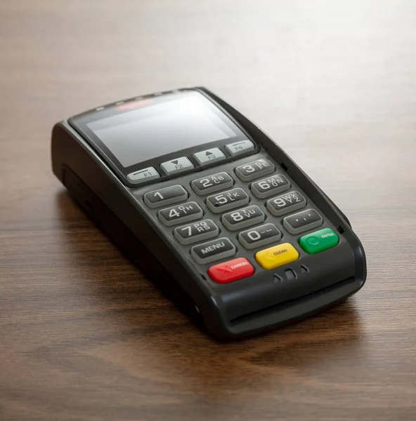 POS terminali ahşap arka planda izole edildi, yakın çekim görüntüsü. Kredi kartıyla ulaşılamayan ödemeler için terminal yazar kasası. Banka ekipmanları, NFC.