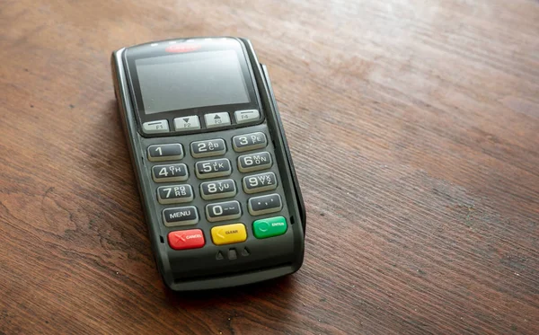 POS terminali ahşap arka planda izole edildi, kopyala alanı. Kredi kartıyla ulaşılamayan ödemeler için terminal yazar kasası. Banka ekipmanları, NFC.