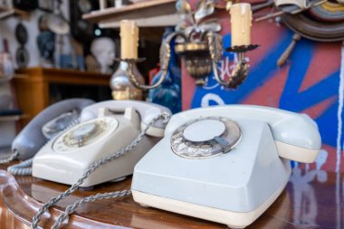 Bit pazarında satılık telefon mahsulü. Ahşap bir masada eski moda telefon cihazları, yakın çekim görüntüsü, bulanık antika mağaza arka planı.