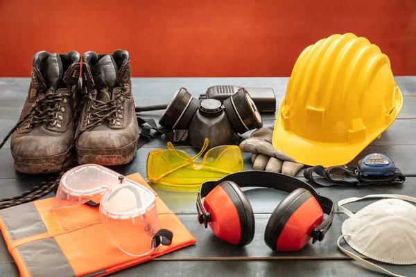 安全生产防护设备 木制桌子上的工业防护装置 红色底色 建筑工地健康与安全概念 — 图库照片