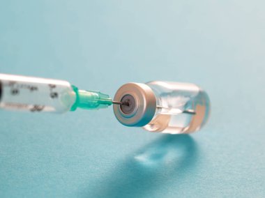 Aşı, koronavirüs aşısı, covid-19 gribi önleme, aşılama konsepti. Viyal doz ve tıbbi şırınga, ilaç iğnesi, pastel mavi arka plan, yakın plan..