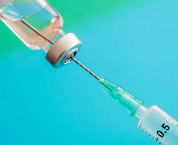 Vaccine, coronavirus vaccination, covid-19 flu prevention, immunization concept. Vial dose and medical syringe, drug medicine shot injection, pastel blue background, closeup.