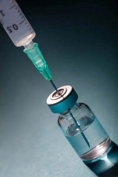 Vaccine, coronavirus vaccination, covid-19 flu prevention, immunization concept. Vial dose and medical syringe, drug medicine shot injection, gray blue background, closeup.