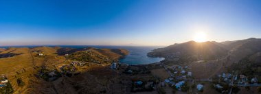 Kea Tzia Adası, Cyclades, Yunanistan. Gün doğumunda Otzias Körfezi Panoraması 'nda. Şafak vakti tepelerin arkasından güneş doğuyor, sakin su, insansız hava aracının hava manzarası.
