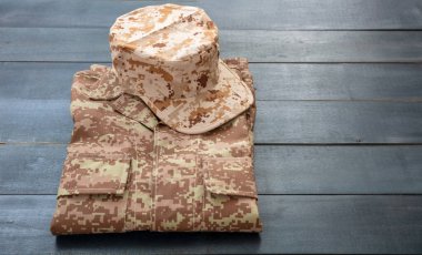 Amerikan ordu şapkası katlanmış üniforma, mavi ahşap arka plan. Askeri kamuflaj dijital çöl desenli gömlek ve başlık.
