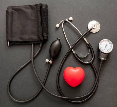 Tansiyon ölçer, hipertansiyon kontrolü. Siyah arkaplan üzerinde tıbbi stetoskop ve sfenometre, üst görünüm.