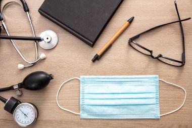 Tıbbi stetoskop sfinometre ve kardiyolog muayenehanesinde koruyucu maske. Coronavirus koruması, sağlık hizmeti konsepti, üst görünüm