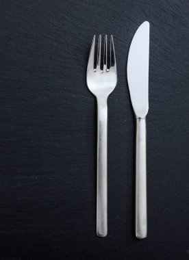 Masa düzenleme, iş yemeği. Çatal ve bıçak siyah zemin üzerinde izole, dikey üst görünüm