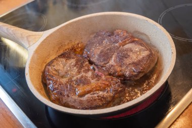 Et konsepti. Taş tavada kızartılmış iki domuz filetosu ve soba yağı. Dilimlenmiş kahverengi biftekler servis edilmeye hazır. Bulanık arkaplan, yakın plan, üst görünüm.