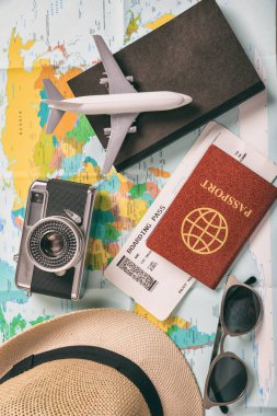 Seyahat ve tatil aksesuarları, harita geçmişi. Turizm seyahati, temel ihtiyaçlar, biletler, pasaport, kitap, kamera, gözlük, şapka. Dikey, üst görünüm.