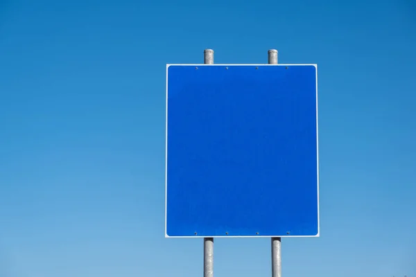Blank road sign on two metal poles, clear blue sky background. Information sign template, copy space