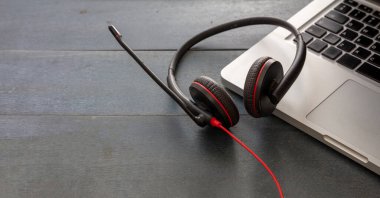 Müşteri hizmetleri desteği, yardım masası, iletişim. Çağrı merkezi ve ofis konsepti. Kulaklık ve dizüstü bilgisayar mavi ahşap masada, yakın çekim görüntüsü, kopyalama alanı,