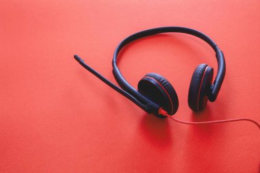 Merkez ofis ve çağrı merkezi konsepti. Müşteri hizmetleri desteği, yardım masası, iletişim. Kırmızı arkaplanda kulaklık siyahı, yakın plan görünümü, kopyalama alanı,