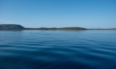 Huzurlu deniz manzarası, sakin mavi su ve Yunanistan 'ın Argolis kentindeki Ermioni yaz tatil köyü yakınlarındaki uzak yeşil tepeler