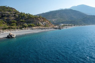 Sahil köyü Sougia ve Yunanistan 'ın güney Girit adasındaki uzun plajı. Sakin deniz ve mavi gökyüzü, engebeli tepeler