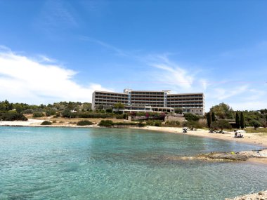 Porto Cheli Yunanistan 'da turkuaz sulara ve kumlu kıyı şeridine bakan sahil beldesi oteli, mavi gökyüzü, güneşli yaz günü