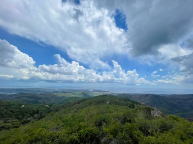 Verimli yeşil dağlar, dramatik bulutların altında güney Küba kıyı şeridine bakan manzara, yükseltilmiş manzara.
