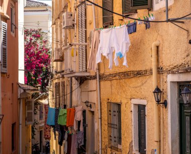 Yunanistan 'ın eski Corfu kasabasının dar sokağında çamaşırhane var. Geleneksel mimari binalar, düşük açı. Akdeniz sokak manzarası