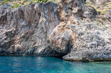 Berrak turkuvaz denizinden yükselen sarp kayalıklar, dalgalanan sulara yansıyan güneş ışığı, Korfu adası Yunanistan, Paleokastritsa