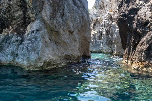 Berrak turkuvaz denizinden yükselen sarp kayalıklar, dalgalanan sulara yansıyan güneş ışığı, Korfu adası Yunanistan, Paleokastritsa