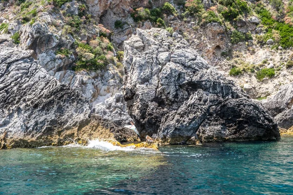 Berrak turkuvaz denizinden yükselen sarp kayalıklar, dalgalanan sulara yansıyan güneş ışığı, Korfu adası Yunanistan, Paleokastritsa