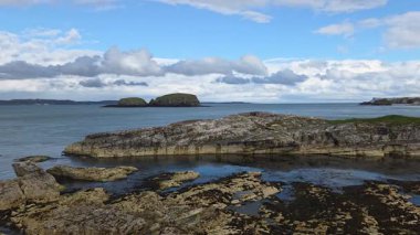 Kuzey İrlanda 'nın Causeway kıyısındaki Ballintoy' da sinematik ışık altında hareket eden engebeli kayalıklı İrlanda deniz manzarası, çarpıcı kaya oluşumları, el değmemiş okyanus suları ve süpüren zaman bulutları..