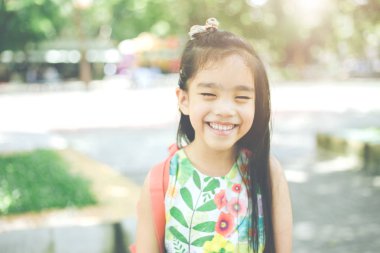 okula dönüş. İlköğretim okulunda okul bahçesinde mutlu gülümseyen kız.