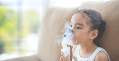 Şirin Asyalı çocuk hasta enhalasyon tedavisi inhaler yumuşak akışı bronchodilator duman maskesi tarafından.