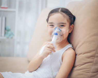 Şirin Asyalı çocuk hasta enhalasyon tedavisi inhaler yumuşak akışı bronchodilator duman maskesi tarafından.