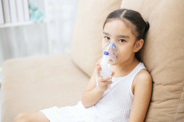 Şirin Asyalı çocuk hasta enhalasyon tedavisi inhaler yumuşak akışı bronchodilator duman maskesi tarafından.