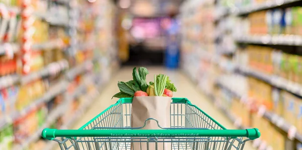 Supermercado pasillo con carro de compras verde vacío — Foto de Stock