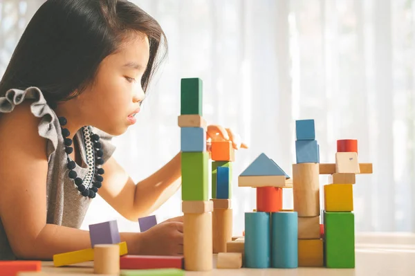 Маленька дівчинка грає з будівельними іграшковими блоками, будуючи буксир — стокове фото