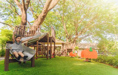 Asyalı çocuk slayt parkta oynarken 