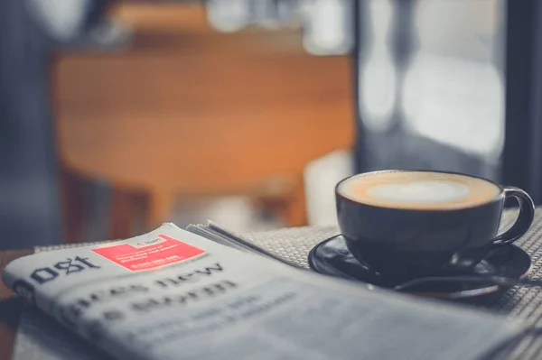 En kopp kaffe och en tidning kaffe på ett träbord — Stockfoto