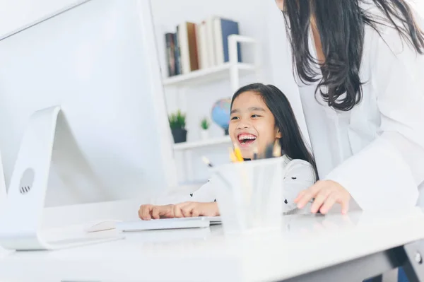 Feliz niña mirando a la computadora con su madre — Foto de Stock