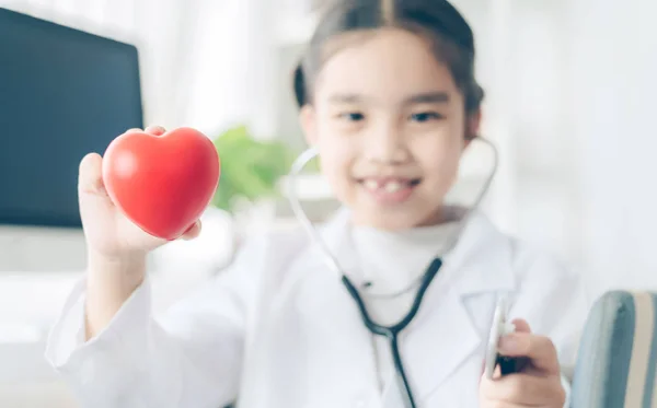 Cuore nelle mani del bambino carino in cappotto medico con stetos — Foto Stock