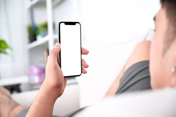 Чоловічі руки тримають телефон з ізольованим екраном на дивані в — стокове фото