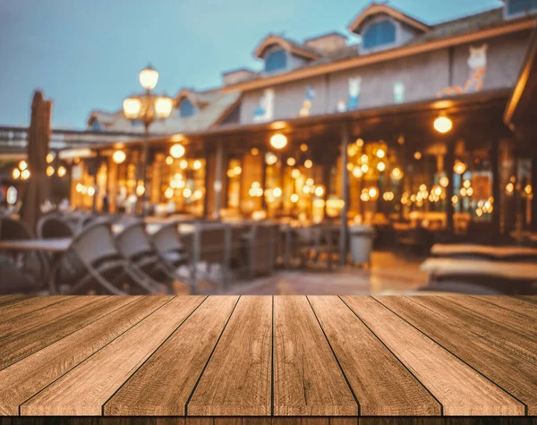 Wooden table in front of abstract blurred restaurant lights back — Stock Photo, Image