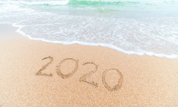 Bonne année 2020 écrit sur le sable du littoral au lever du soleil concept . — Photo