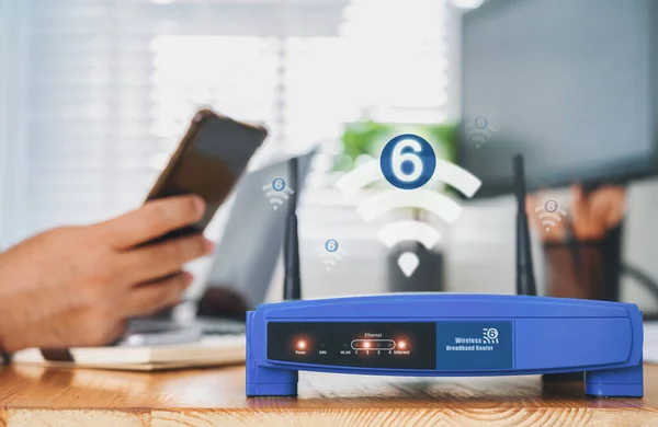 closeup of a wireless router With wifi 6 technology and a man using smartphone on living room at home ofiice