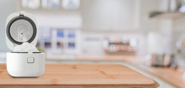 Ahşap mutfak yüzeyinde taze pirinç içeren modern elektrikli pilav pişirici. Kumaş peçete ve bulanık iç zemin..