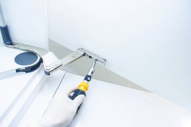 Erkek eli tornavida tutuyor ve dolap kapısını tamir ediyor.