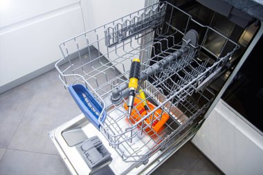 repair of a modern dishwasher with screwdrivers in the kitchen clipart