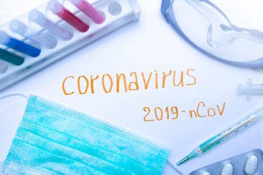 Coronavirus tanı ve tedavi analiz konsepti. Solunum maskeli bir laboratuar masası, steteskop, kan tüpleri, tabletler. Covid 2019