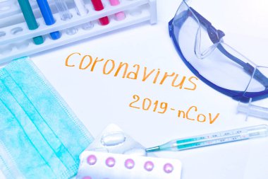 Coronavirus tanı ve tedavi analiz konsepti. Solunum maskeli bir laboratuar masası, steteskop, kan tüpleri, tabletler. Covid 2019