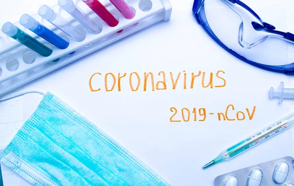 Coronavirus tanı ve tedavi analiz konsepti. Solunum maskeli bir laboratuar masası, steteskop, kan tüpleri, tabletler. Covid 2019