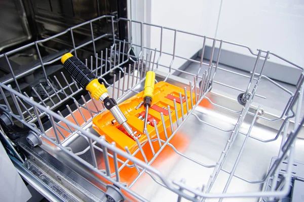 repair of a modern dishwasher with screwdrivers in the kitchen